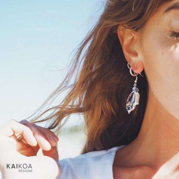 Blonde woman wearing ocean beach inspired sea shell shaped silver earrings made in Australia