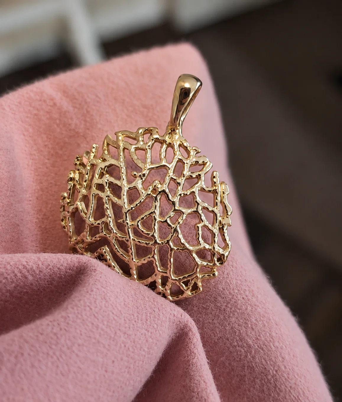Gold sea fan pendant on a soft pink cloth