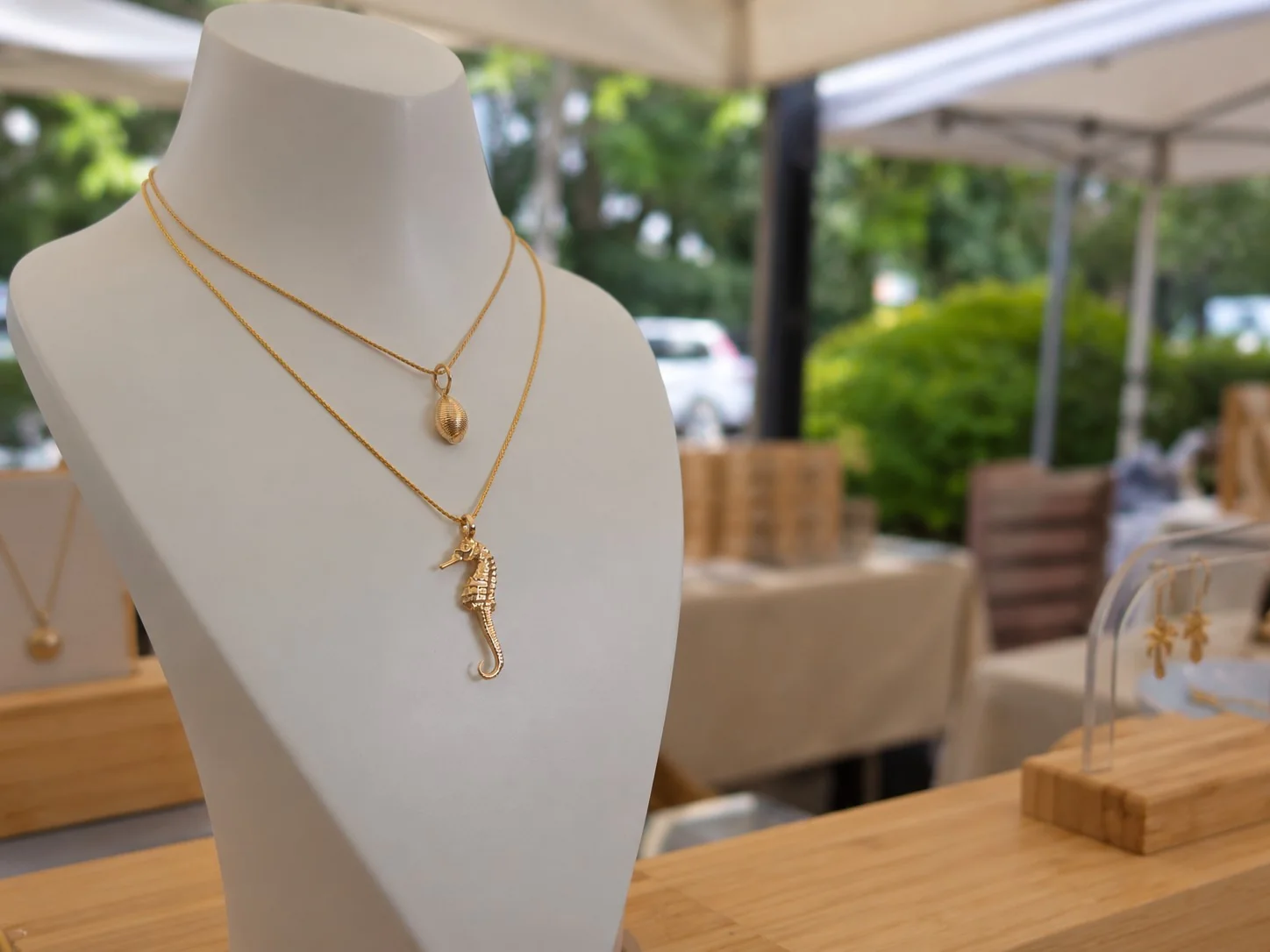 Gold shell and seahorse pendants on jewellery display stands