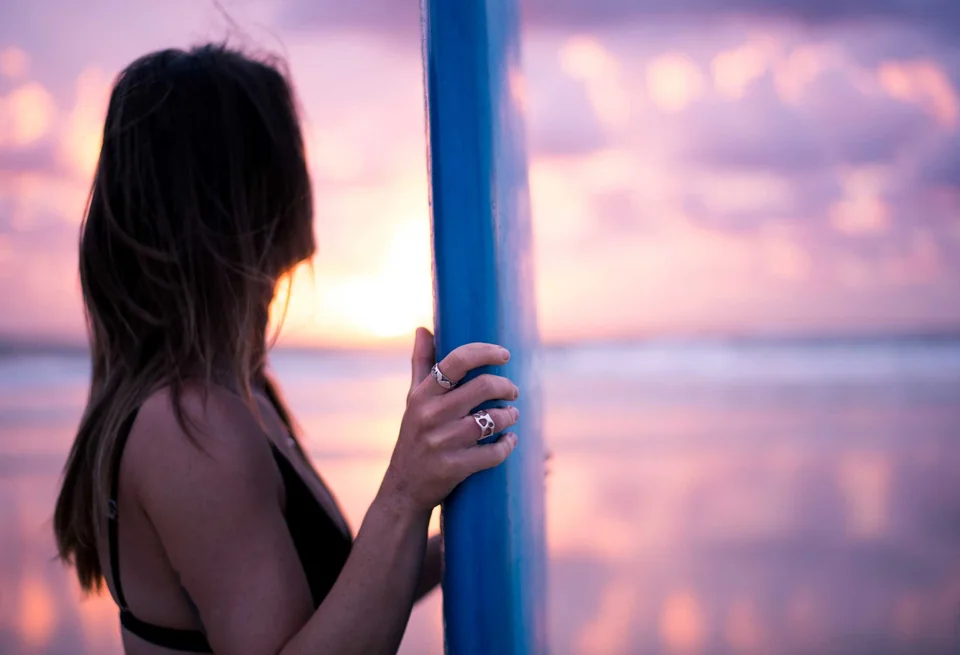 Woman holding a surfboard at sunset