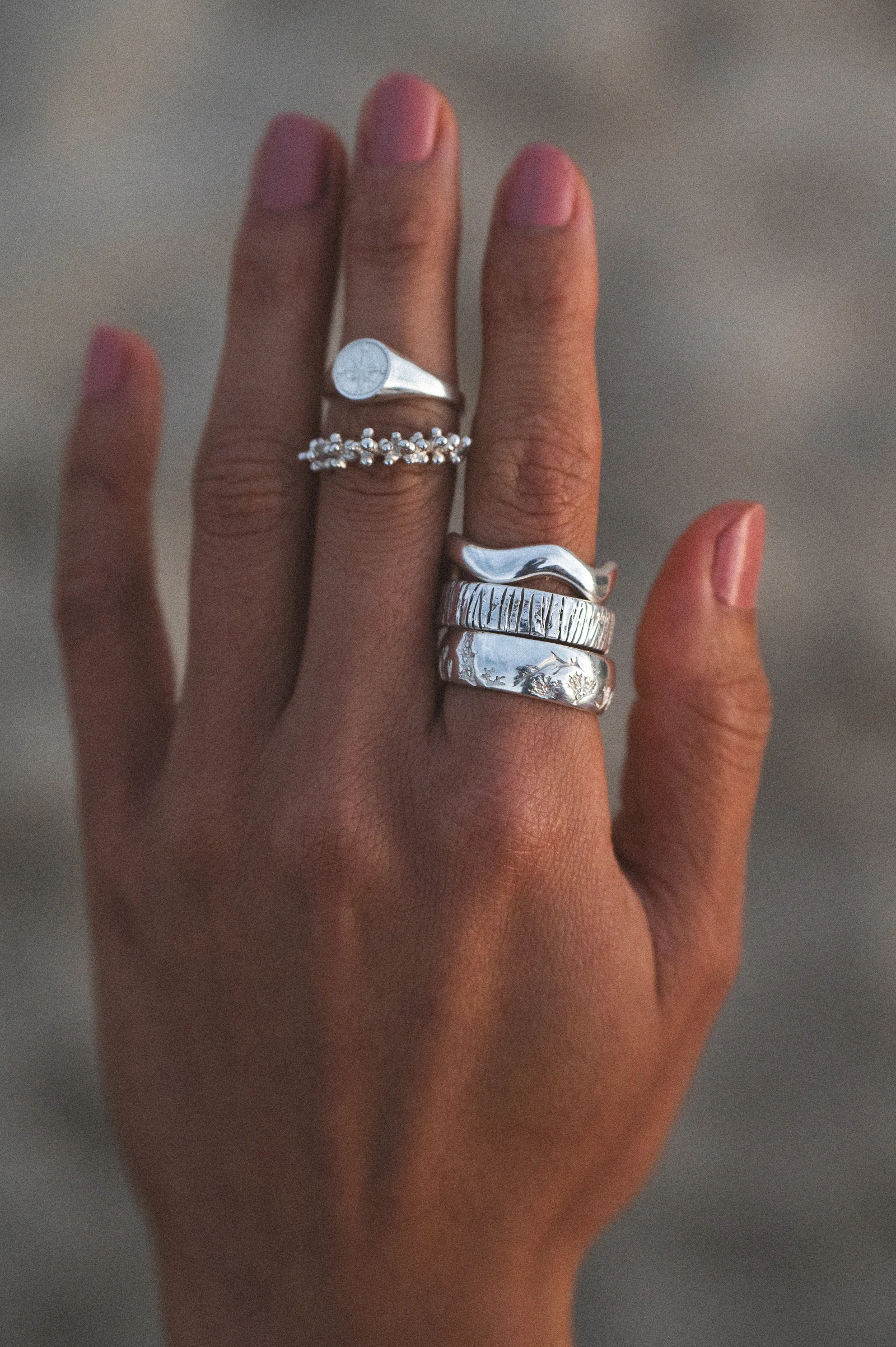 Hands wearing stacked sterling silver ocean rings