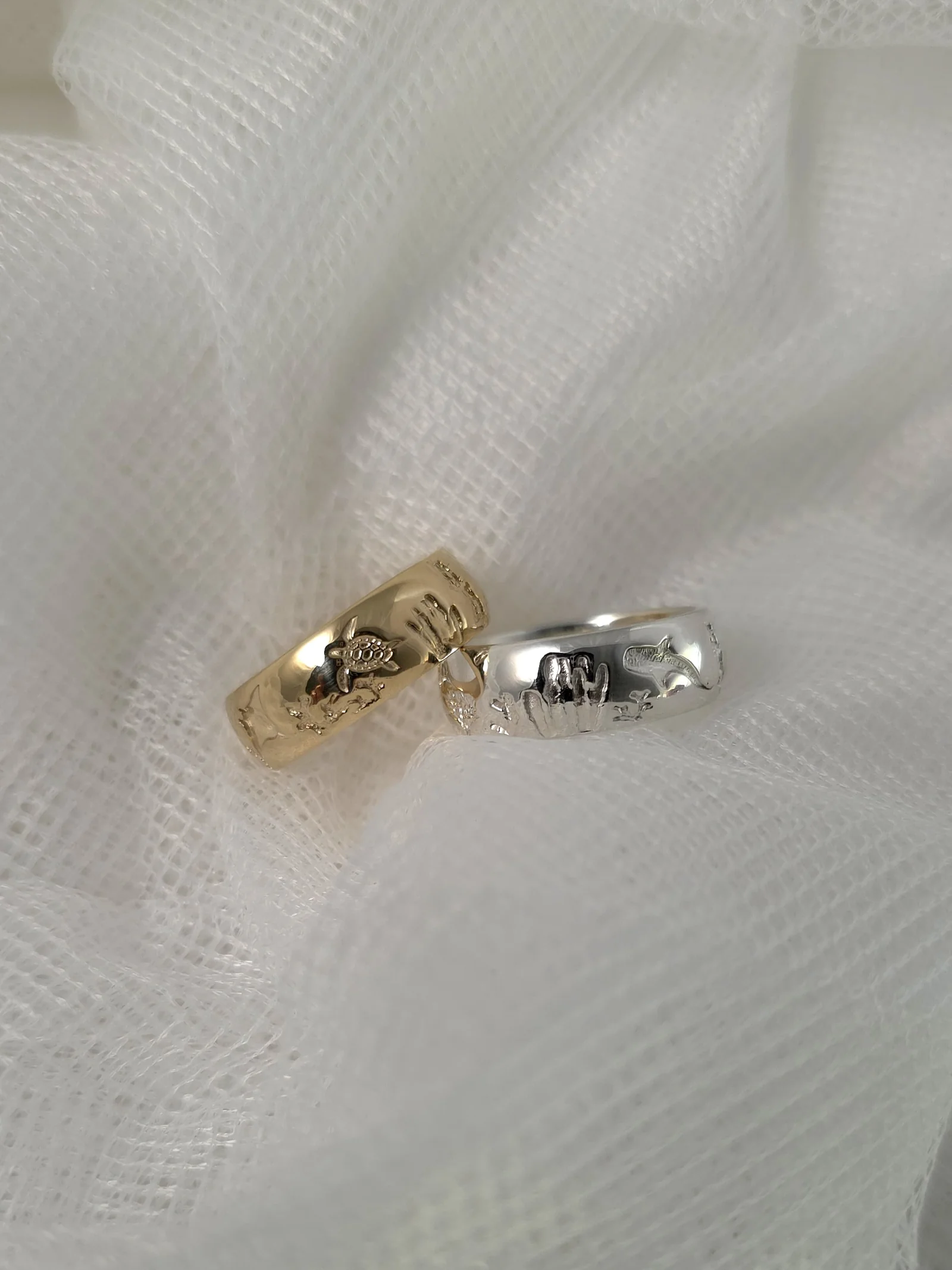 Solid silver and gold reef rings on white fabric