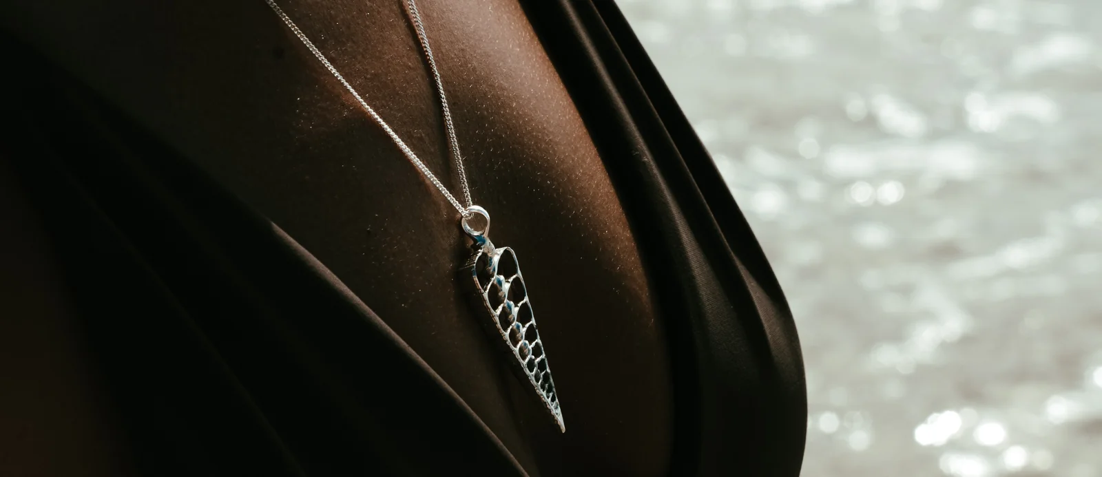 Surfer with wet hair wearing layered sterling silver ocean pendants