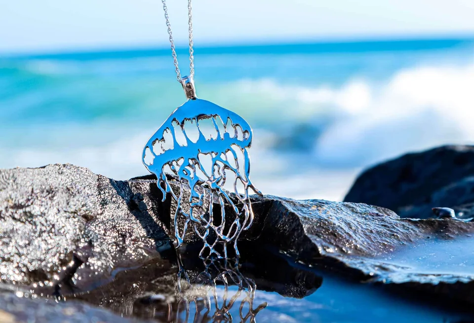 Sterling silver jellyfish pendant on a rock by the sea