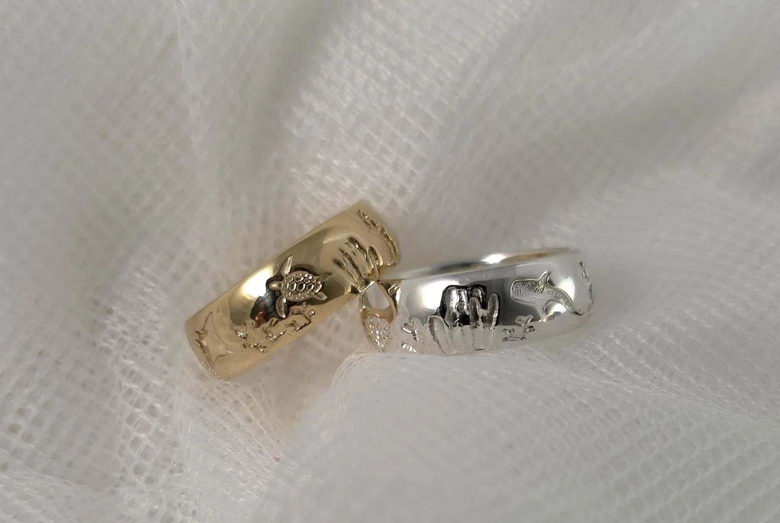 Solid gold and sterling silver Reef rings resting on white linen