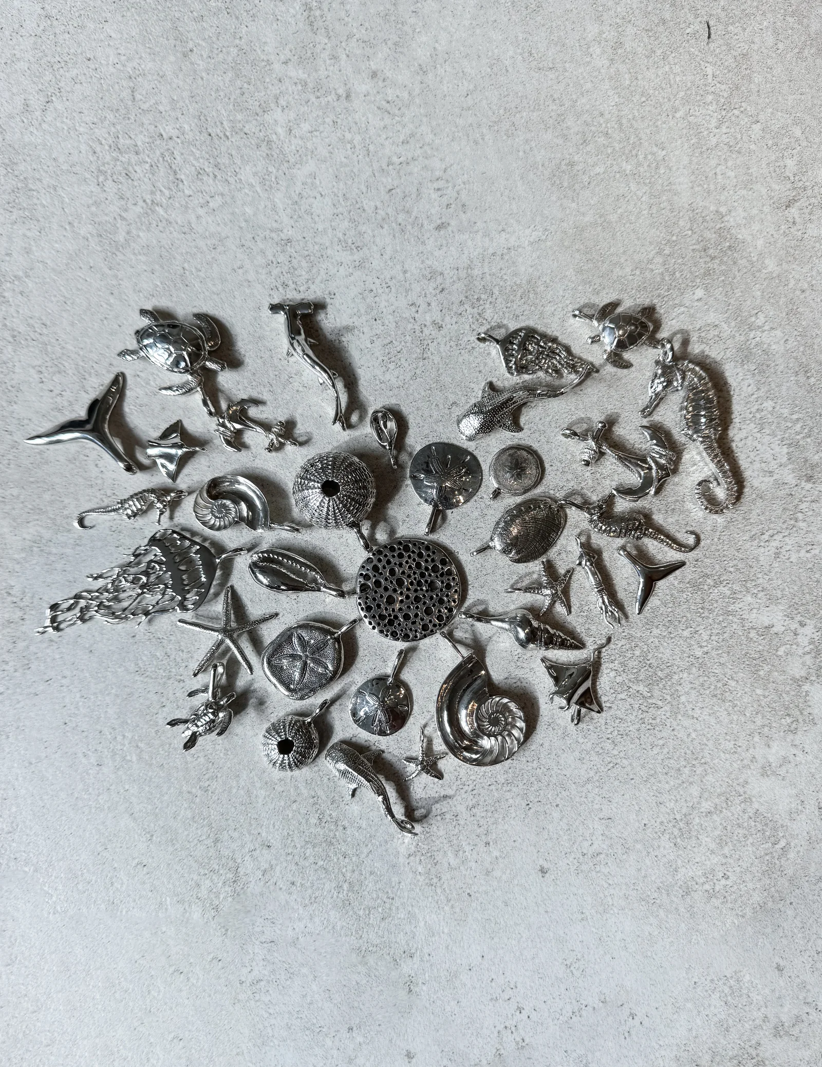 Ocean-inspired silver pendants arranged in a heart
