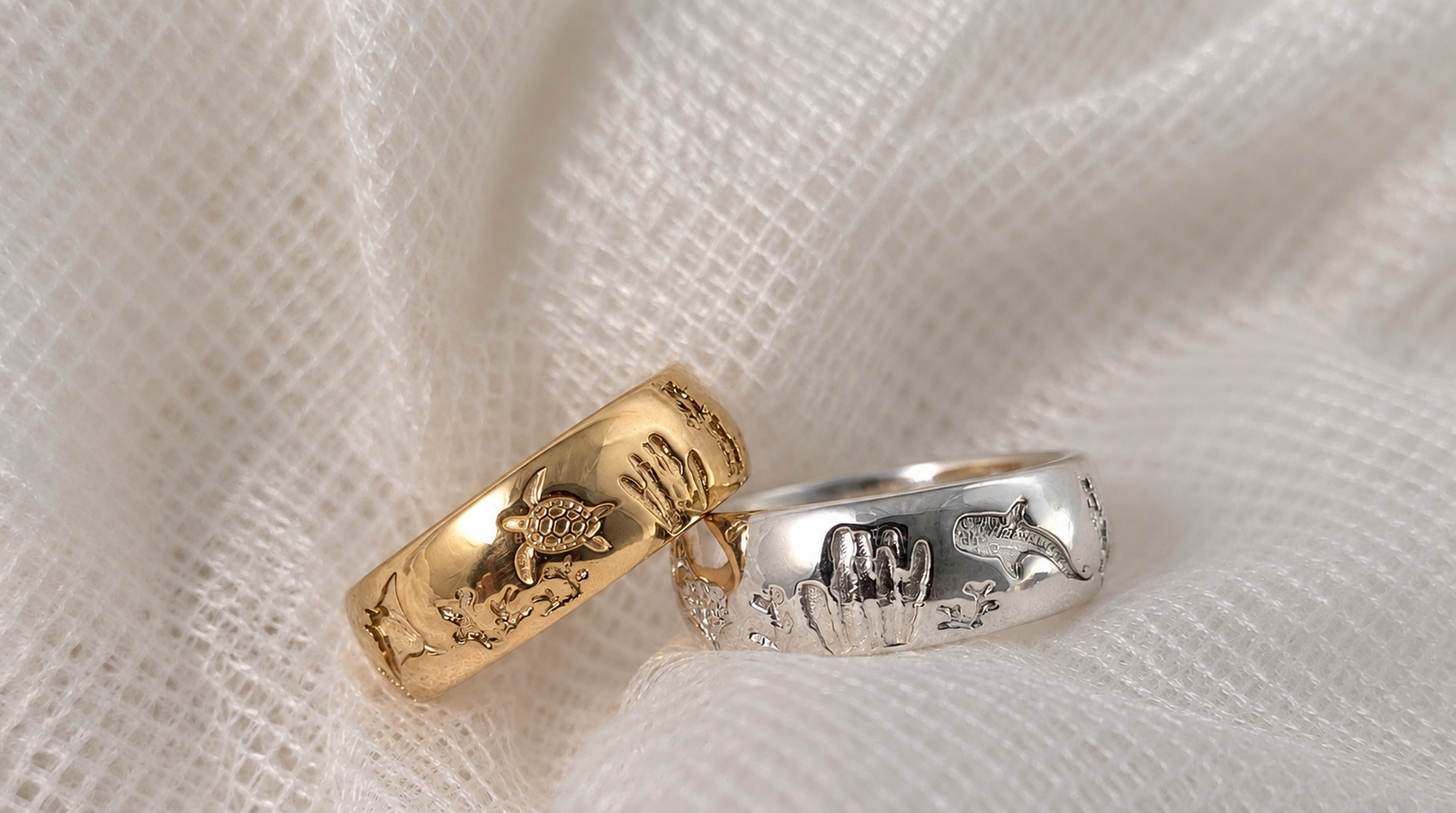 Gold and sterling silver Ocean Reef rings on soft cream fabric